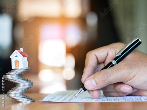 House on coins stack and human hand signs purchase agreement for a house