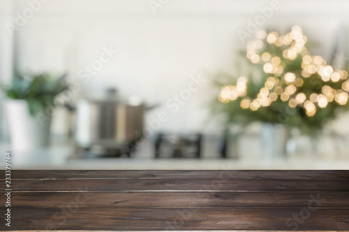 Empty wooden tabletop for display products and blurred kitchen with Christmas tree as background.