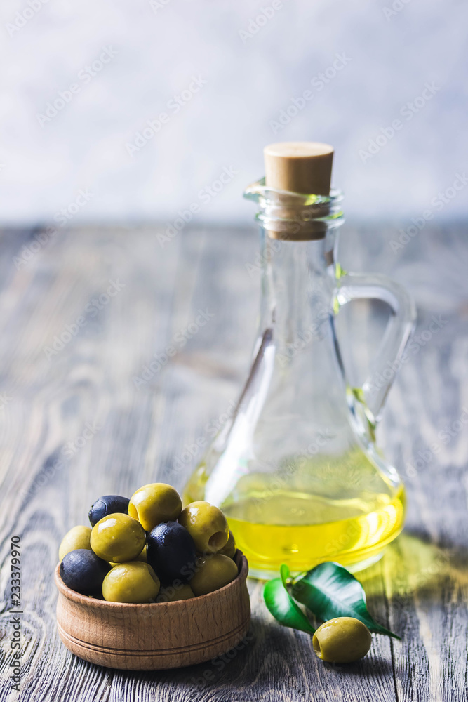Extra vergin olive oil in glass jar, marinated olives in wooden bowl on rustic background. Selective focus, space for text. Extra vergin olive oil in glass jar, marinated olives in wooden bowl on rustic background. Selective focus, space for text.