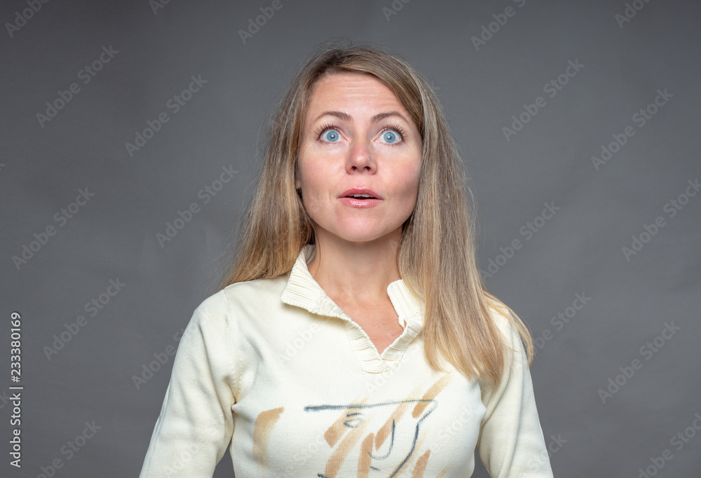 Emotional woman. Surprised and astonished adult girl. Woman looking up surprised in full belief. Positive human emotion. Portrait of european woman isolated on gray background, shooting in studio. Emotional woman. Surprised and astonished adult girl. Woman looking up surprised in full belief. Positive human emotion. Portrait of european woman isolated on gray background, shooting in studio.