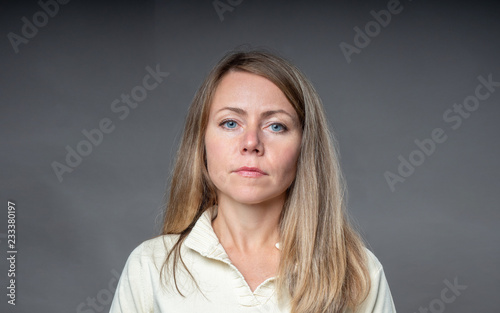 Portrait of blonde woman isolated on gray background. Affable face close-up. Portrait of adult girl shooting in studio.