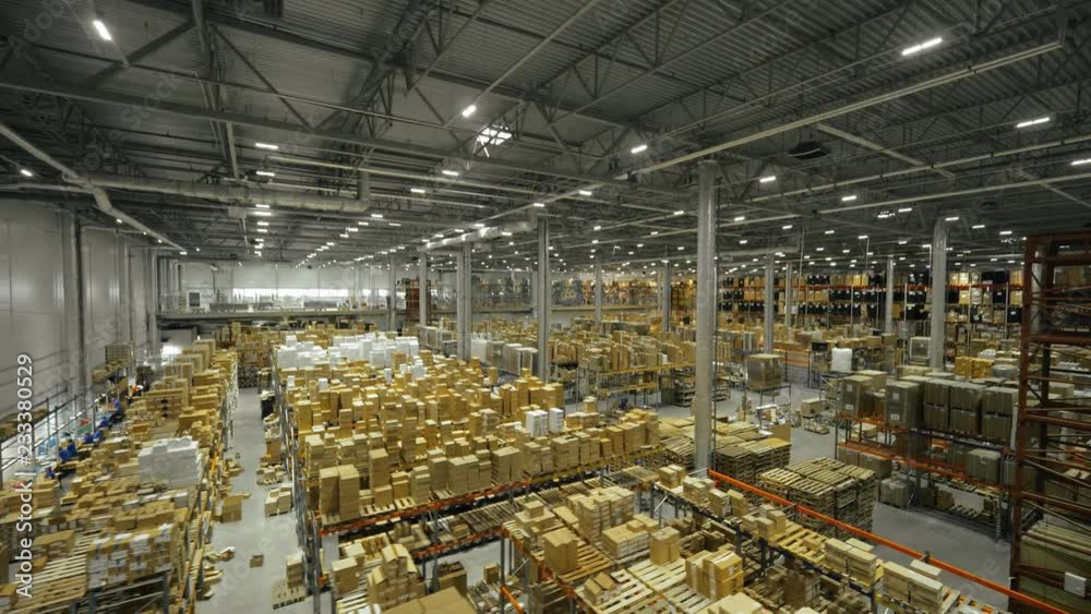 Boxes stored on high shelves in large industrial warehouse drone view