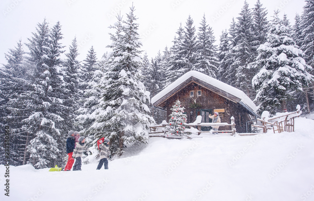 Austria, Altenmarkt-Zauchensee, family with sledges at wooden house at Christmas time