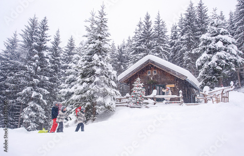 Austria, Altenmarkt-Zauchensee, family with sledges at wooden house at Christmas time © Westend61