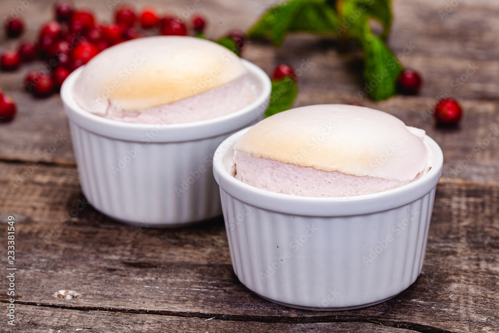Souffle with cranberries in white ramekin on wooden rustic table. Close up Souffle with cranberries in white ramekin on wooden rustic table. Close up