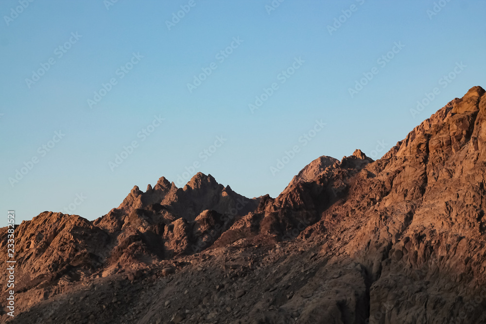 Veduta di un picco che si intravede in lontananza, tutto attorno le rosse montagne del deserto in Giordania