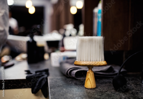 A hair dust brush and other tools in hair salon for men, barbershop interior.