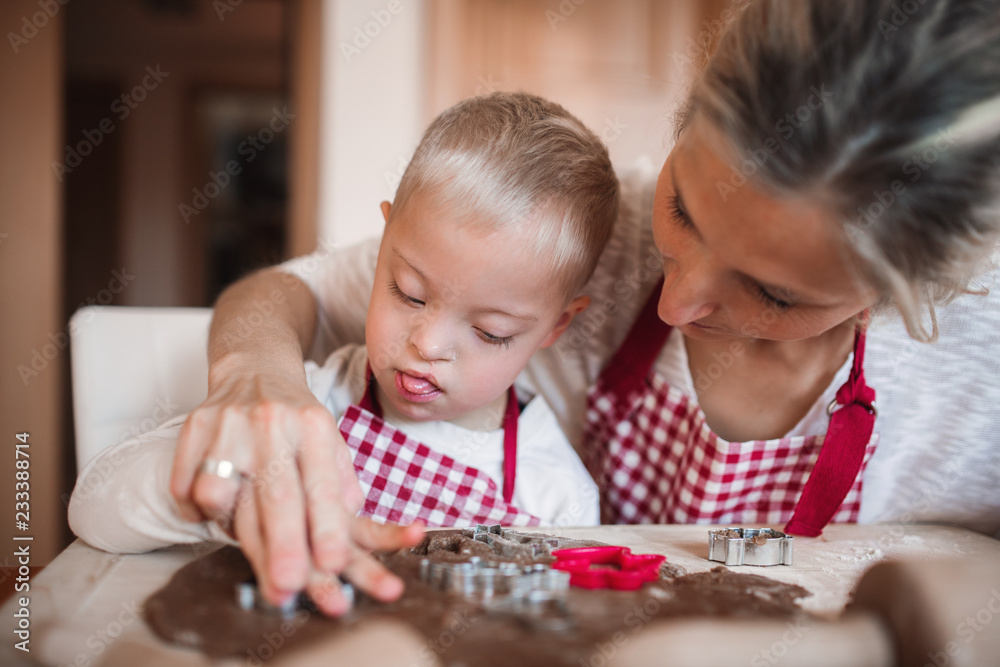 A handicapped down syndrome boy with his mother indoors baking. A handicapped down syndrome boy with his mother indoors baking.