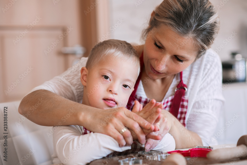 A handicapped down syndrome boy with his mother indoors baking. A handicapped down syndrome boy with his mother indoors baking.