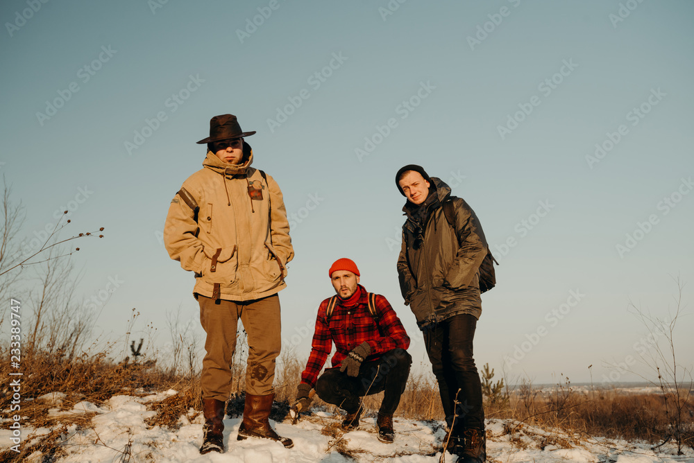 Three friends stand on a hill during a beautiful sunset. Winter trip. Relax and meeting friends. Friendship and longevity. 