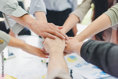 A group of Asian businessmen are discussing their work. Everyone joins hands.