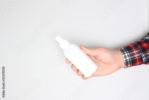 bottle with spray in hand on light background
