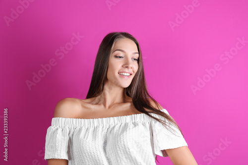 Portrait of beautiful young woman laughing on color background