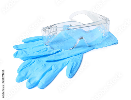 Medical gloves and safety glasses on white background