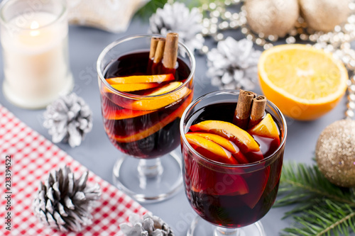 Two glasses of hot mulled wine with spices and sliced orange. Christmas drink with candle and decorations. Top view