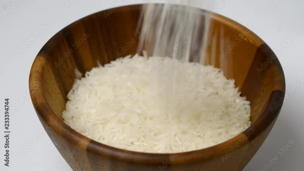 Rice grains falling into wooden bowl Rice grains falling into wooden bowl