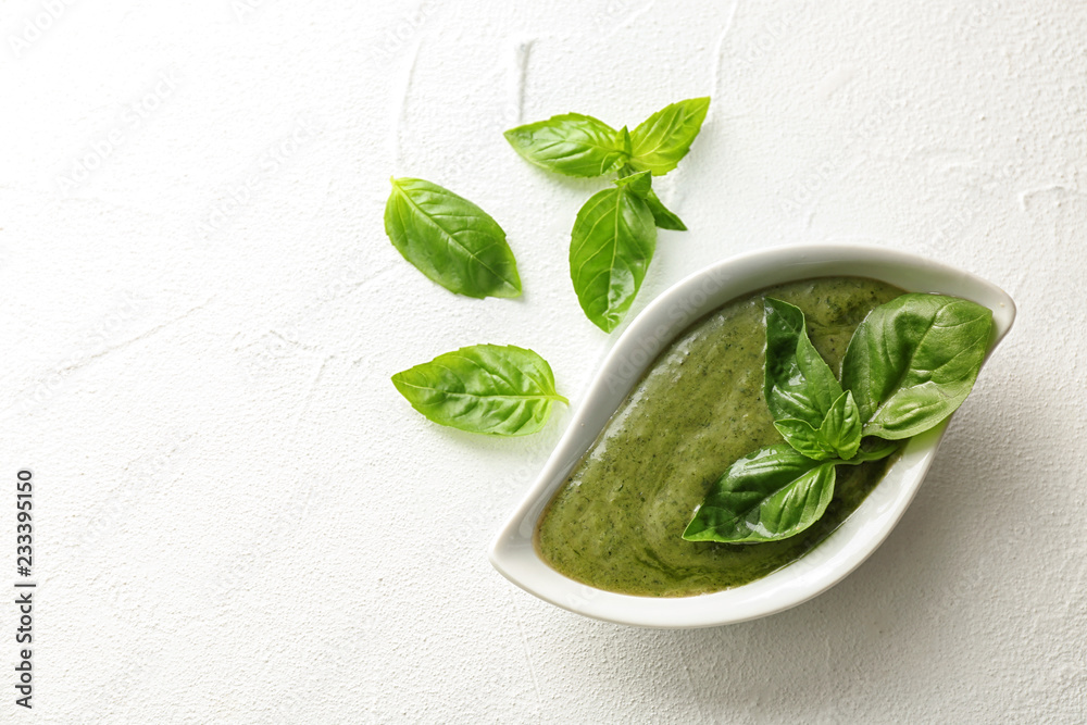 Obraz premium Sauce in gravy boat and basil leaves on white table, top view