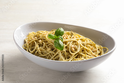 Plate of delicious basil pesto pasta on white background