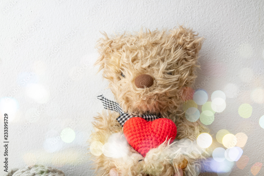 Fototapeta premium Teddy bear holding a heart-shaped pillow with plank wood on white background , concept valentine