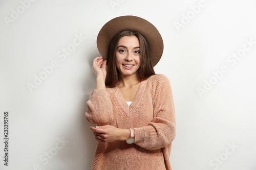 Piękna młoda kobieta w ciepłym pulowerze z kapeluszem na białym tle