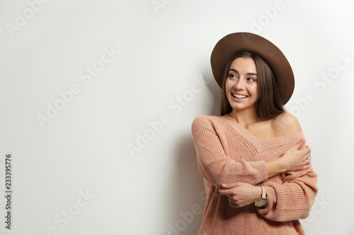 Beautiful young woman in warm sweater with hat on white background. Space for text