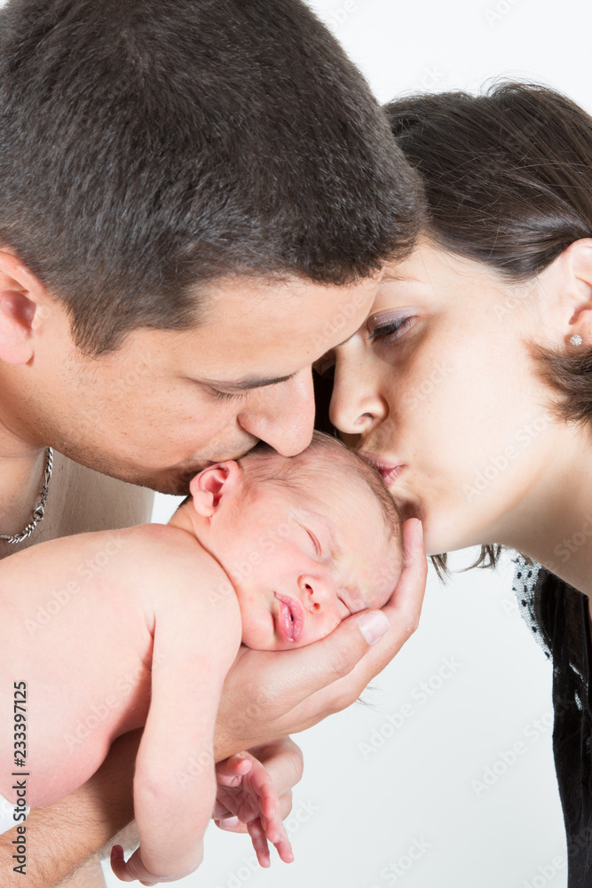 Young mother and father with newborn sleeping baby family kiss Young mother and father with newborn sleeping baby family kiss