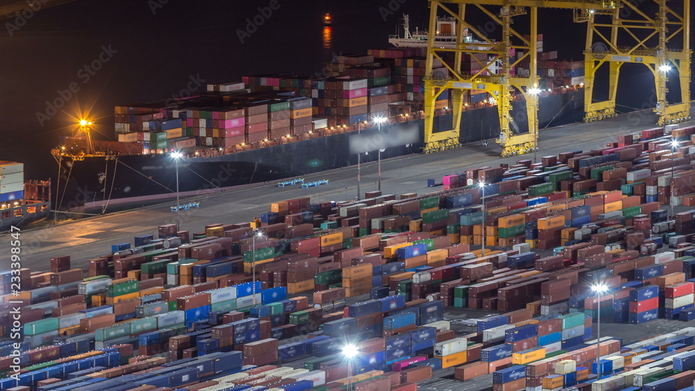 Seaport and loading docks at the port with cranes and multi-colored cargo containers night timelapse