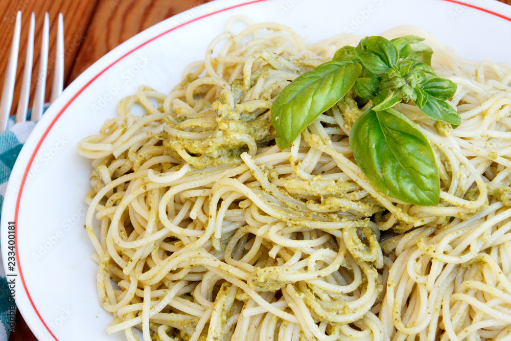 Spaghetti with pesto sauce and basil garnish
