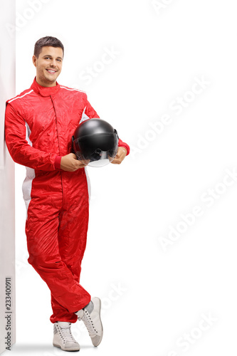 Racer holding a helmet and leaning against a wall