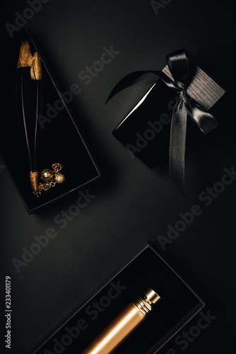top view of bottled perfumes and decorative feathers on black