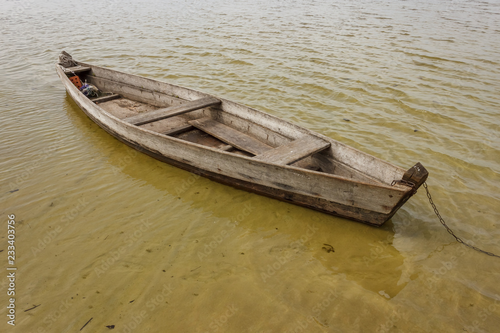 Old wooden fishing boat moored in the shallow waters of the lake Old wooden fishing boat moored in the shallow waters of the lake