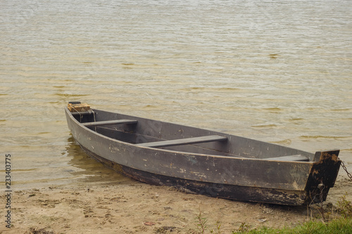Old rural wooden, fishing boat moored in the shallow waters of the lake Fototapet