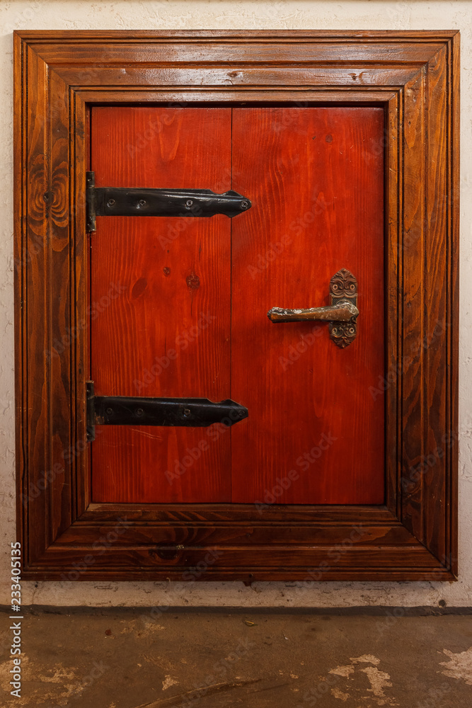 Obraz premium Wooden door of red color with metal hinges of black color. Built-in door