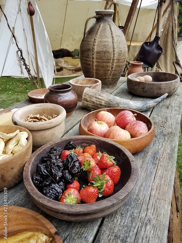 A table set up with bowls of fresh and dried fruit, Viking era pottery and a drinking horn. 