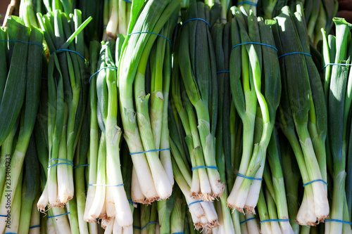 Green onions, fresh bundles lay on the counter of a village market.