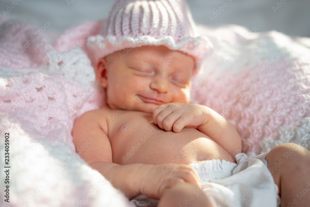 Newborn baby girl in a pink hat on a pink and white blanket Newborn baby girl in a pink hat on a pink and white blanket