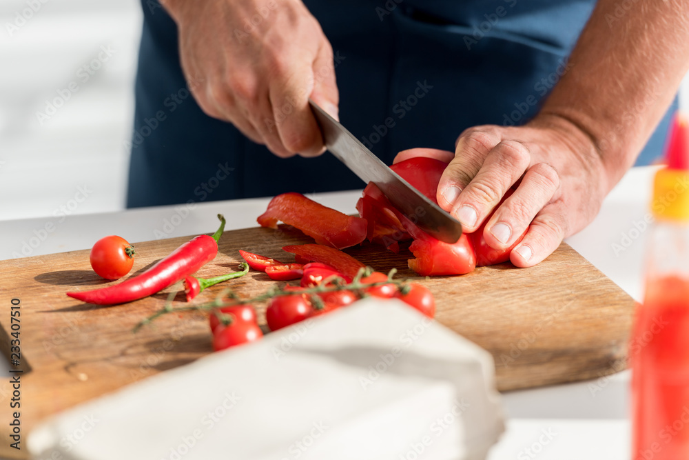 close up view of male hands cutting chili peppers on chopping board close up view of male hands cutting chili peppers on chopping board