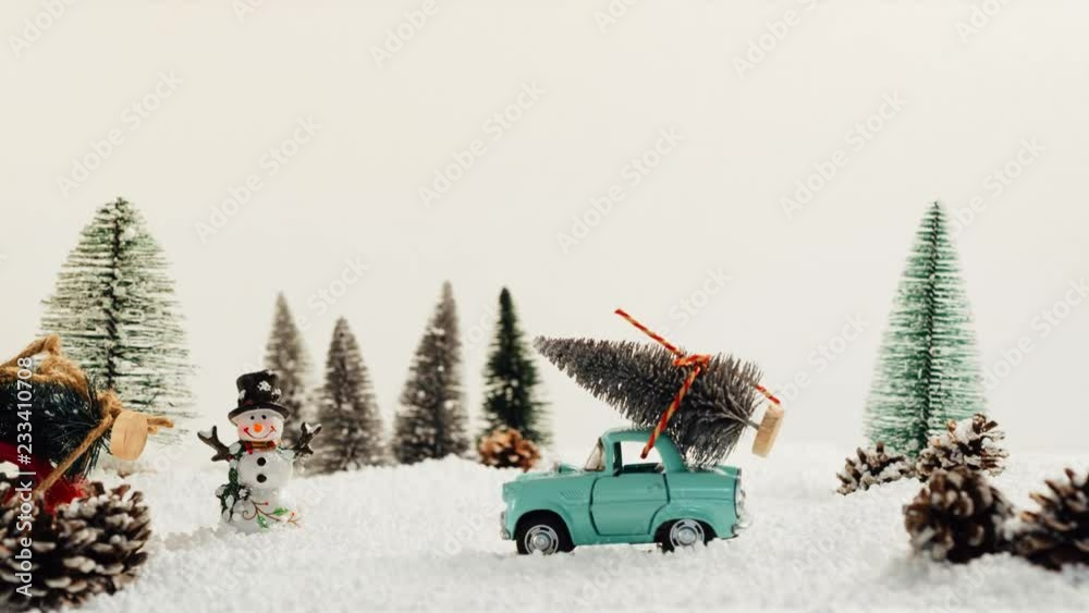 Toy cars carrying Christmas tree in snowy and winter landscape
