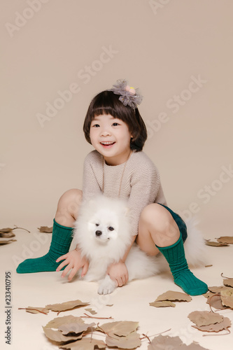 Little pretty Asian girl sitting in an autumn background.