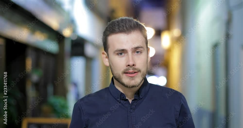 Front view of a happy man talking at camera in the night in the street