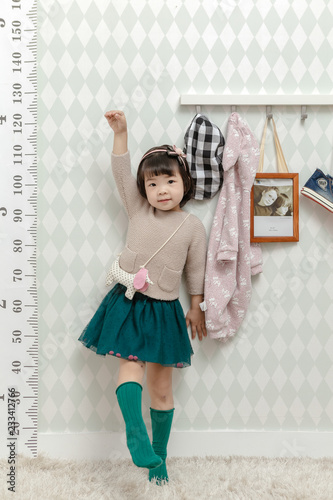 Little pretty Asian girl standing in a normal indoor life background.