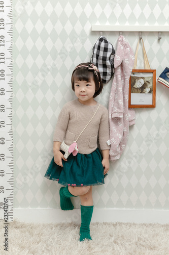 Little pretty Asian girl standing in a normal indoor life background.