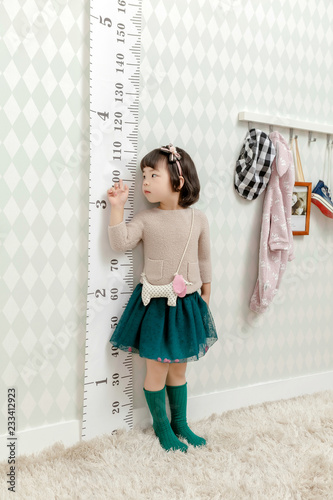 Little pretty Asian girl standing in a normal indoor life background.