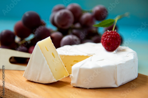 cheese camembert with raspberries and grapes on table