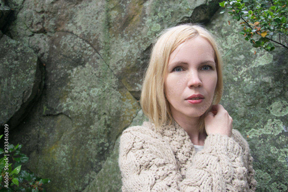 A woman in a warm jacket on a background of stone. A woman in a warm jacket on a background of stone.