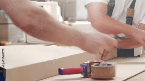 Two people pack the goods in cardboard packaging