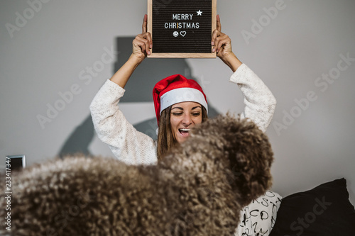 .Young, funny and happy woman playing with her nice brown spanish water dog. Celebrating Christmas time and wearing tematic costumes. Lifestyle. photo