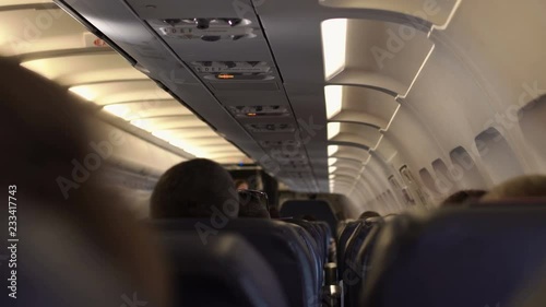 Interior airplane, point of view as passenger from coach seats as travelers depart plane.