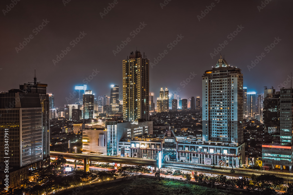 Illuminated high-rises line the horizon in downtown Jakarta Indonesia at night.