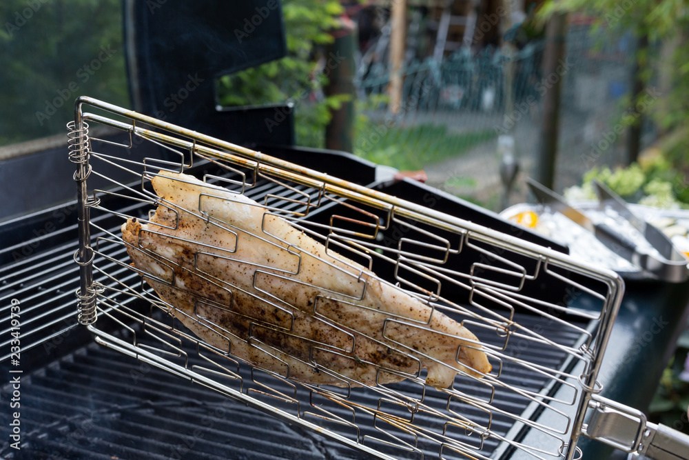 Gegrillter Fisch wird im Grillgitter auf einem Gas Grill im Garten ... Gegrillter Fisch wird im Grillgitter auf einem Gas Grill im Garten ...